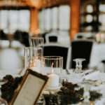 Table pour un mariage en hiver avec des bougies, le menu, des pommes de pin, des branches de sapin