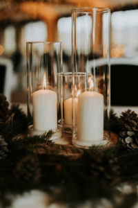 Table pour un mariage en hiver avec des bougies, des branches de sapin, des pommes de pin